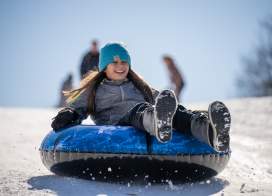 girl on sled going down snow hill