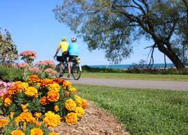 Mariner's Trail couple on tandem bike with orange flowers in foreground