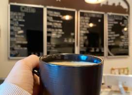 Coffee cup held in front of Manitowoc Coffee menu