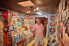 A person browsing in an antique store, looking at a wall of posters and signs.