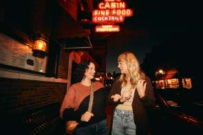 Two people on Main Street, standing in front of a neon sign.