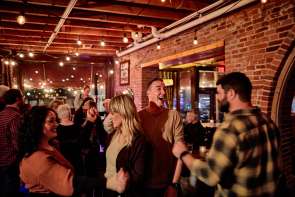 People in a busy bar with a brick wall behind them.