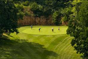 Image of four people on a green at a golf course.