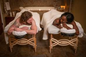 Two people laying on massage tables, smiling at one another.