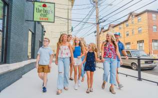 A group of people walking away from the bug's ear boutique sign in Downtown Elizabethtown