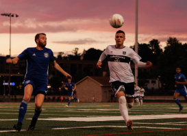 A Bavarian United SC player running after a ball with his opponent.