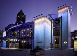 Exterior of the Marcus Performing Arts Center, glowing blue, orange and pink in the evening.