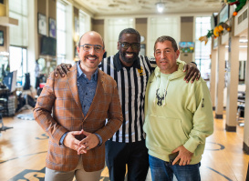 Three men standing together with arms around each other's shoulders at Gee's, smiling at the camera.