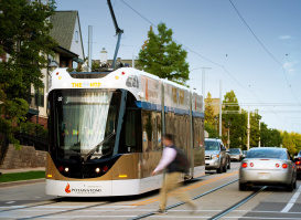 street car on road, cars and pedestrians passing