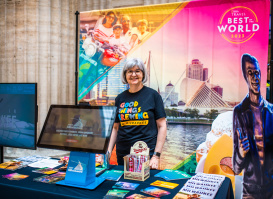 smiling volunteer stands by Visit Milwaukee display at union station