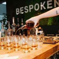 A person pouring bourbon to a set of glasses.