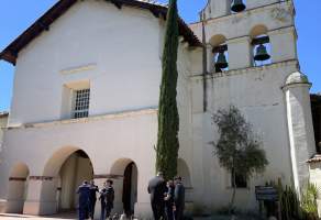 San Juan Bautista Mission. People stand in front of the Mission entryway and Bell Tower.