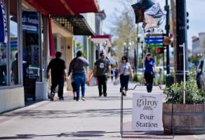 people walk along the sidewalk downtown by businesses