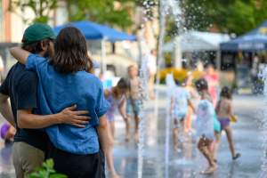 couple embracing as they watch kids splash in a fountain
