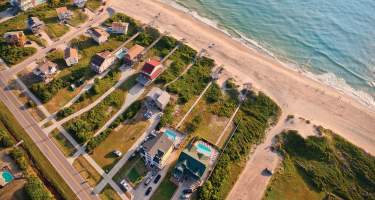 An aerial shot of beach-front rental homes situated on the coast of the Outer Banks in North Carolina.