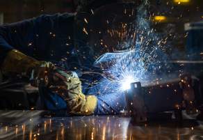 A worker in PPE welding in a shop.