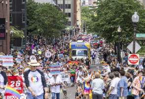 people walking down the street in celebration of the Pride Parde. featuring the mobile VIC.