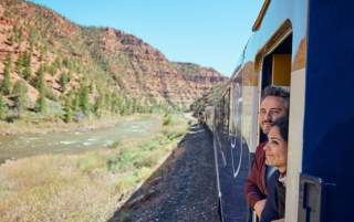 Two guests on the Canyon Spirit railway line looking out of the train in Utah.