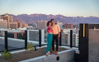 Couple standing and taking a selfie on the roof at Van Ryder with Salt Lake City Skyline and wasatch mountains in the background