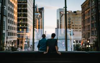 Two people sitting on a bench in the walkway at City Creek over main street looking down Main street