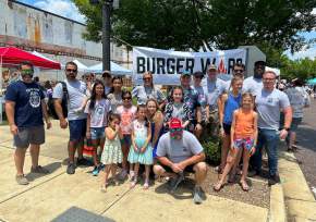 group of attendees in front of the burger war banner