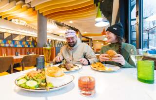 A couple eating at Seventy One with plates and drinks on the table in front of them.