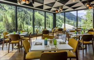Interior view of SeventyOne with tables and chairs set and full length windows overlooking the mountains