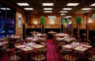 Interior image of the Steak Pit. Tables and chairs with warm wood paneling
