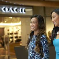 Woman and Friend in Vibrant Blue Shirts Smiling and Walking Past Coach Store