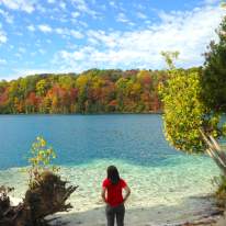 Woman in Red Shirt Gazing at Beautiful Blue Water on a Fall Day at Green Lakes State Park