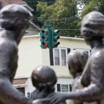 Close-up of Four Statues with Upside-Down Traffic Light in Background