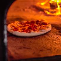 a pizza being cooked in a wood fired oven