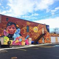 Colorful mural of faces and flowers on side of Syracuse Building