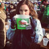 A woman drinking green beer out of a pitcher