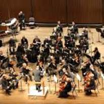 Symphony Orchestra playing a concert with big violins in the front of the stage