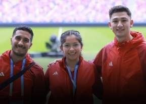 3 people wearing matching jackets and posing for the camera in front of a field