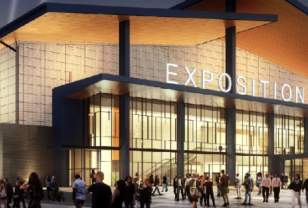 Rendering of the NYS Fair Expositon center lit up in golden hue at night, with walls of glass windows,modern elements, and a crowd of people standing outside main enterence