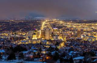 Aerial view of Salt Lake at night looking south down main street from above the capitol building. The city is lit up with yellow lights.