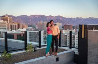 Couple standing and taking a selfie on the roof at Van Ryder with Salt Lake City Skyline and wasatch mountains in the background