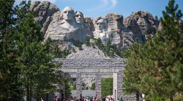 People walking through the memorial with Mount Rushmore in the background