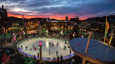 People ice skating at Main Street Square in downtown Rapid City, SD surrounded by holiday lights.