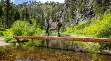 Two hikers cross a bridge on the spring creek portion of the centennial trail in south dakota