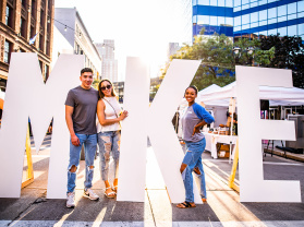 friends posing by big MKE letters at the Westown Night Market
