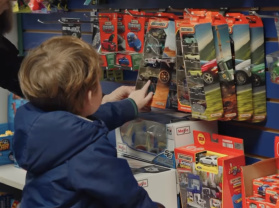 child look at a wall of toys in store