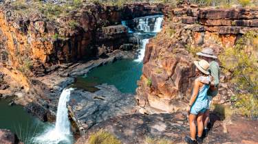 Hikers stand at the lookout point for Punamii-Unpuu (Mitchell Falls) with a view of three tiers of the falls