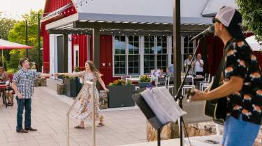 A couple dances joyfully while live music plays at Aubrey Vineyards in Overland Park, KS