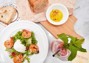 A plated shrimp salad and bread with drink at Louie Bossi in Fort Lauderdale, FL