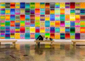 A man laying on a bench in front of the Happy Exhibit at NSU Art Museum