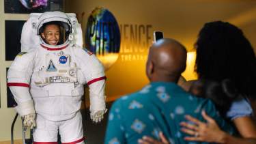 Family fun at INFINITY Science Center with child in astronaut suit with parents looking on