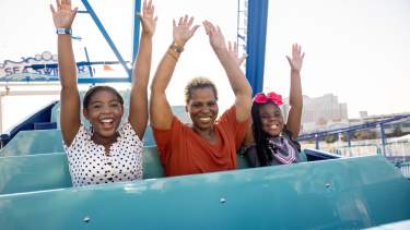 African American family of three on amusement park ride at Paradise Pier Fun Park